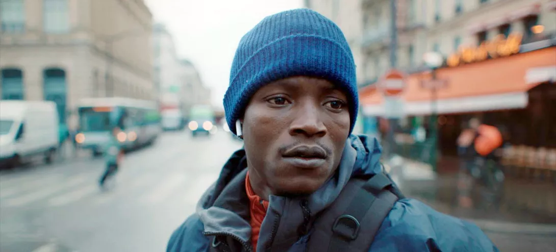 Scène du film L'Histoire de Souleymane où l'on voit l'acteur principal en gros plan dans une rue de Paris
