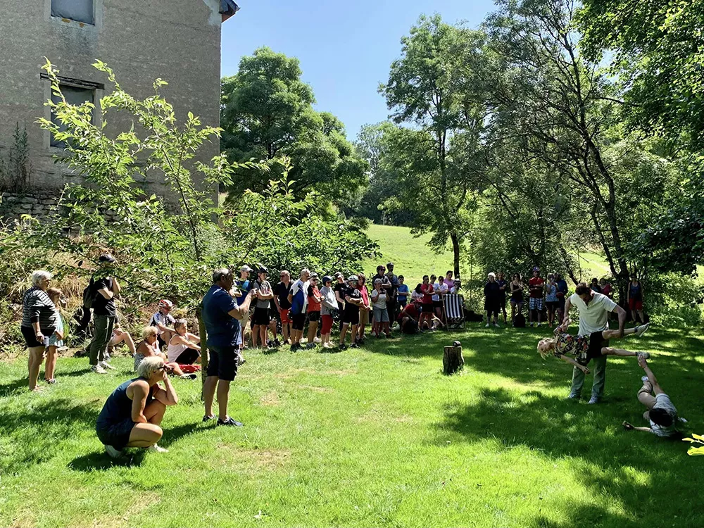 Des spectateurs installés sur l'herbe en extérieur regardent des danseurs.